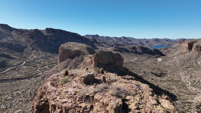 Aerial view of rugged canyons and mountains with a winding road cutting through the arid landscape under a clear blue sky, Apache Junction, Arizona, United States.