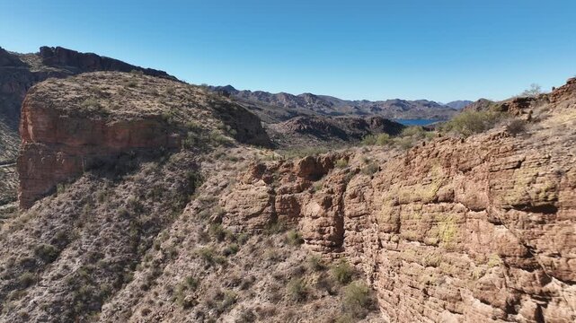 Aerial view of rugged mountains and a serene lake, with stark contrasts of brown rock and the clear blue sky, Apache Junction, Arizona, United States.