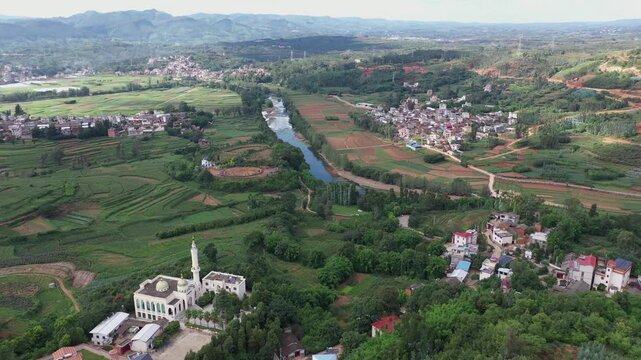 Aerial view of a mosque and river cutting through the lush landscape, with scattered buildings and fields, Kunming, Yunnan, China.