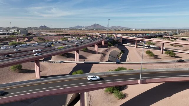 Aerial view of a complex highway intersection with cars, bridges, and concrete canal cuts through the arid landscape, Mesa, Arizona, United States.