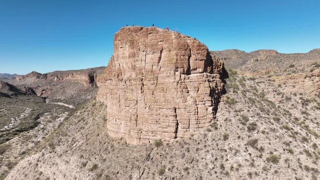 Aerial view of a towering rock formation, its textured surface contrasting against the clear blue sky, Apache Junction, Arizona, United States.
