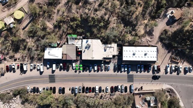 Aerial view of buildings nestled amongst rocky terrain, cars parked along the roadside, creating a contrast against the desert landscape, Apache Junction, Arizona, United States.