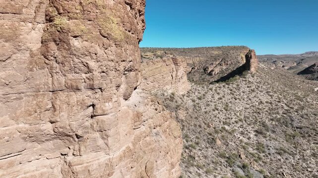 Aerial view of rugged canyons and sparse desert vegetation under a clear blue sky creating a textured, undulating landscape, Apache Junction, Arizona, United States.