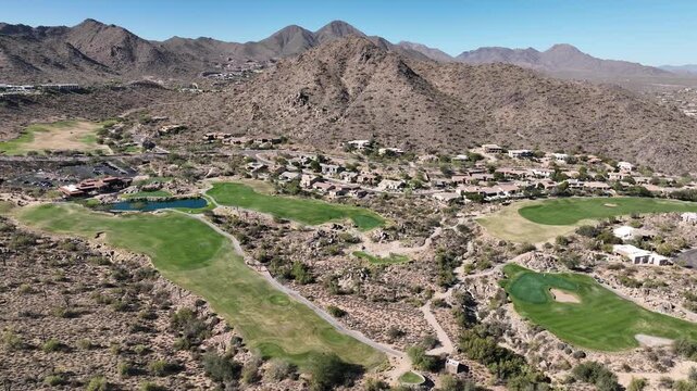 Aerial view of a lush golf course nestled amongst the arid desert landscape and rugged mountains, creating a striking contrast, Fountain Hills, Arizona, United States.