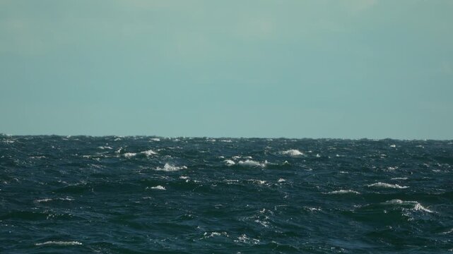 Sea waves, water, rough dark blue ocean under light blue sky outdoor