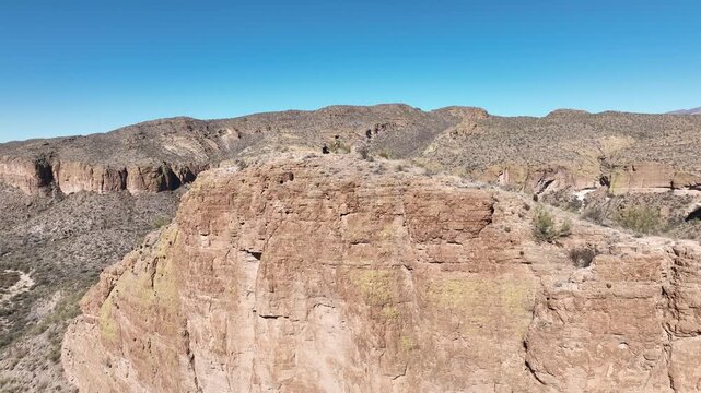 Aerial view of rugged mountains, a cliff, and a lake under a clear blue sky, showcasing the natural beauty of the landscape, Apache Junction, Arizona, United States.