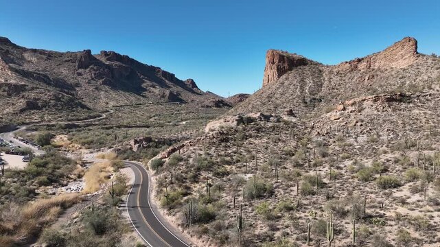 Aerial view of the arid mountainous terrain with sparse vegetation and a winding road cutting through the landscape, Apache Junction, Arizona, United States.