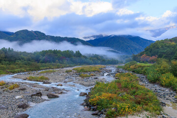 秋の早朝の白馬の山々にかかる霞と松川