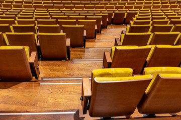 Closeup of yellow seats in empty audience music hall with stairs between rows. Performing arts and theatre entertainment venue