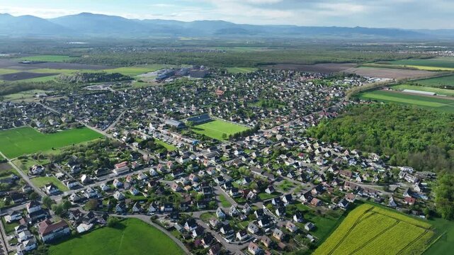 Aerial view of the landscape with green fields, houses, and a football field, creating a vibrant mix of rural and urban elements, Wittenheim, Grand Est, France.
