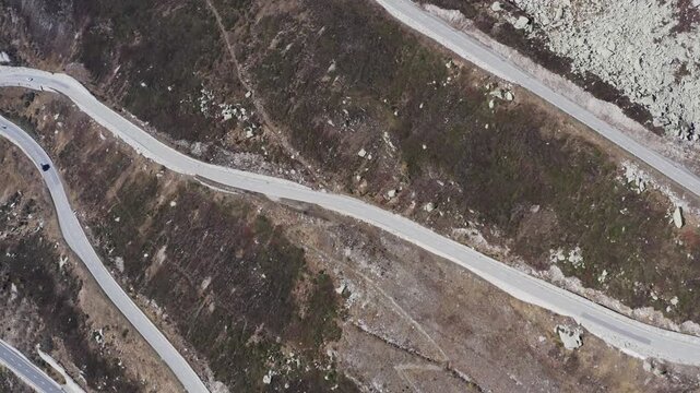 Aerial view of winding roads snaking through the rugged, mountainous terrain under a bright sky, Obergoms, Valais, Switzerland.