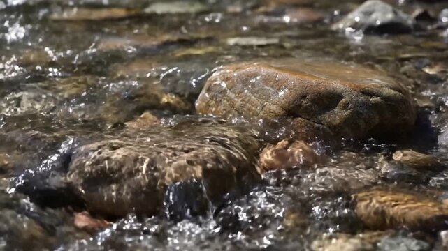 Dynamic shot of a powerful waterfall cascading over rugged, moss covered granite boulders, creating mist, spray, and strong currents. Capturing the raw energy and constant motion of water as it?