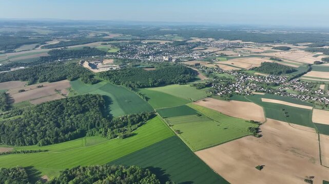 Aerial view of Zillisheim with its patchwork of green and brown fields, dense forests, and scattered houses, creating a picturesque landscape, Zillisheim, Grand Est, France.