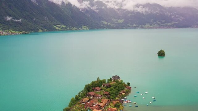 Aerial view of iseltwald village on the shores of turquoise Lake Brienz, surrounded by green mountains under a cloudy sky, Lake Brienz, Canton of Bern, Switzerland.