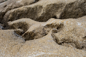 a dry, arid landscape featuring undulating, sandy hills with a textured surface of small, coarse pebbles and sparse patches of grass