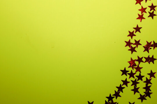 ​A bright and unconventional lime-green background framed on the right by a vertical strip of sparkling red or burgundy star confetti.