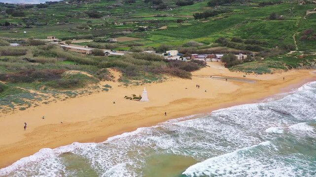 Aerial view of the sandy shores of Ramla Bay where the white statue stands in contrast to the blue water and the green vegetation, Gozo Island, Gozo, Malta.