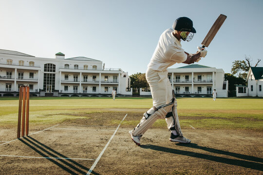 Cricket player making a batting shot on a field during a match