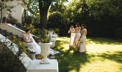Bride and bridesmaids gathering outdoors in a garden wedding setting
