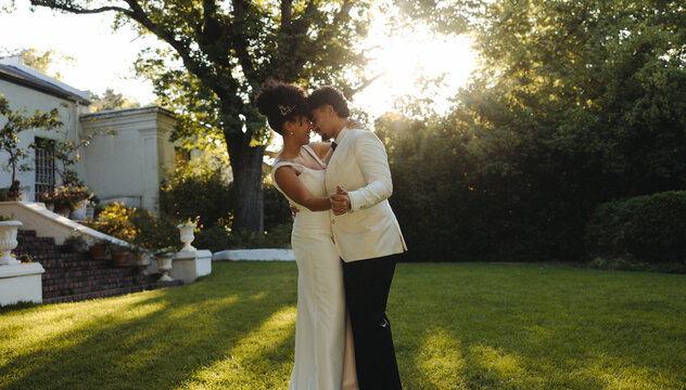 Wedding couple dancing in a scenic outdoor garden during golden hour