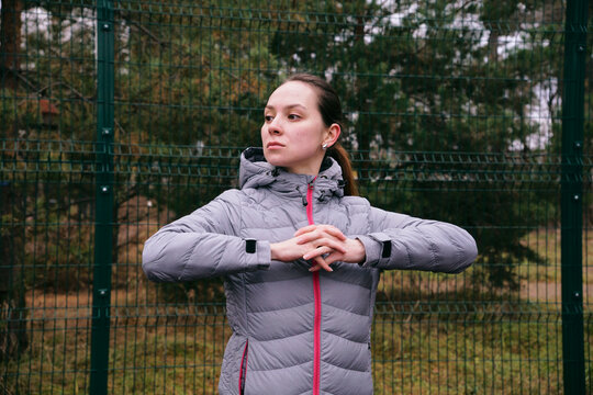 A young woman on a sports field is doing muscle stretching exercises. Warm-up before training. Outdoor training - Powered by Adobe