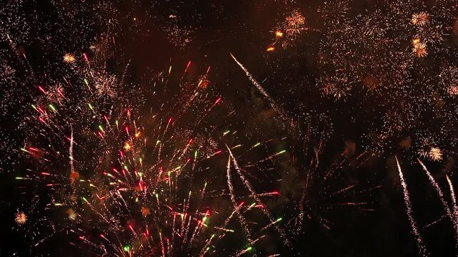 Multiple fireworks exploding with bright sparks in the dark night sky