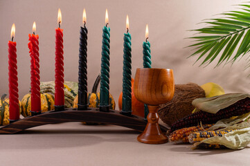 Happy Kwanzaa. Seven candles red, black and green on a natural wooden background. Harvest and gifts. Symbols of African heritage.