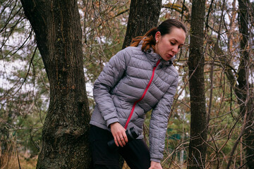 A young woman is resting after a run in the forest. Breathing after exercise