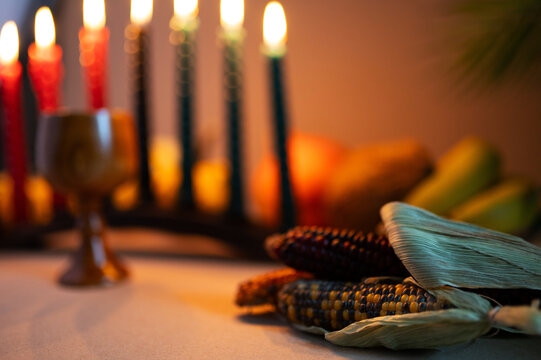 Happy Kwanzaa. Seven candles red, black and green on a natural wooden background. Harvest and gifts. Symbols of African heritage.