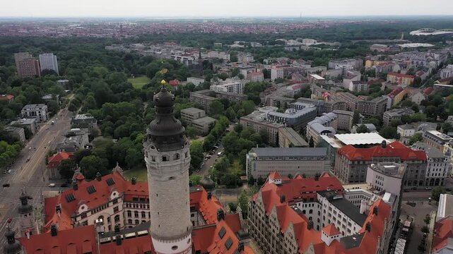 Aerial view of the Neues Rathaus tower with its red roofs contrasting with the green trees and the city skyline beyond, leipzig, Saxony, Germany.