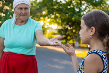 Obraz premium Grandmother and child are studying the snail in the park. Selective focus.