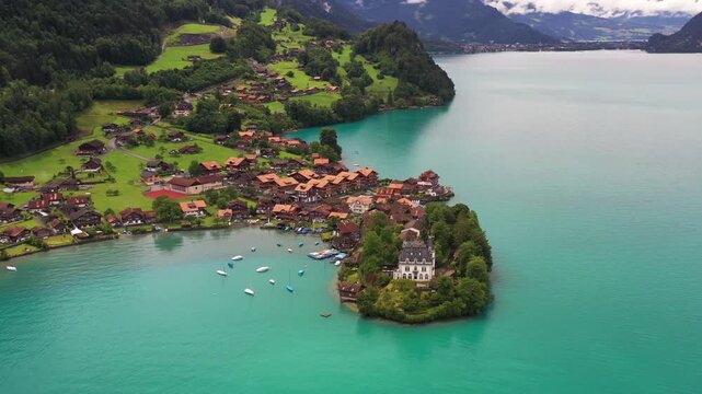 Aerial view of the Iseltwald peninsula, with its clustered houses and boats dotting the turquoise waters of lake Brienz, Iseltwald, Canton of Bern, Switzerland.