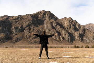 Man embracing mountains in vast open landscape