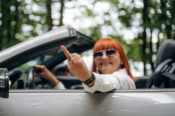 Middle finger gesture. Side view of woman that is driving convertible cabriolet car