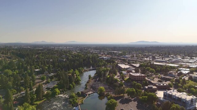 Aerial view of Deschutes River winding through a city, contrasting the urban landscape with the natural river and lush green trees, Bend, Oregon, United States.