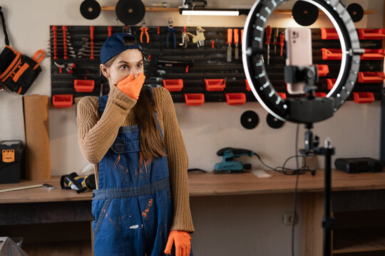 Shocked Craftsman or artisan blogger with ring light and smartphone streaming in workshop with assortment tools with bad news say omg. Face expression in wow. Blogging, industry and technology - Powered by Adobe