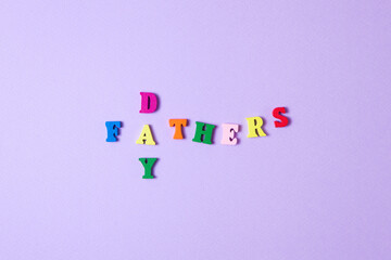 Child's toy letters spelling Fathers Day on purple background. Concept photo. Flat lay design.
