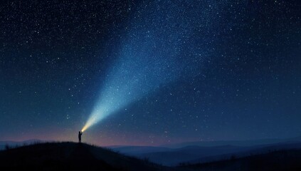Person shines flashlight on vast starry night sky from a hill