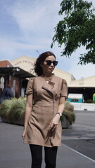 Fototapeta premium Stylish woman walking in the city wearing sunglasses and beige outfit