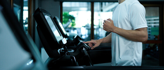Man's finger adjusts settings, increasing speed or starting a workout in a fitness center.
