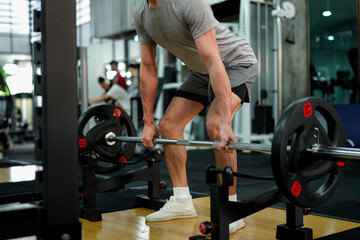 muscular body builder sport man is practice weight training on squat barbell for core muscle inside gym with dark background for exercising and workout usage
