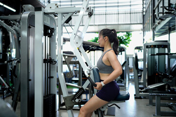 woman using exercise machine during sports training in health club