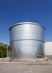 Close-Up Cylindrical Metal Storage Tank at Industrial Facility Near Warehouse.  Heavy Industry Infrastructure in Gniezno Poland