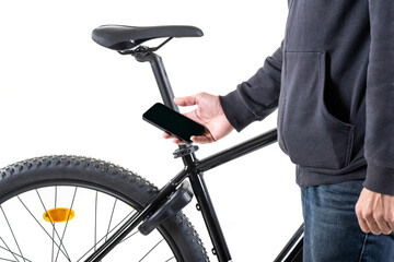 Unrecognizable male hand with a mobile phone, against the background of an electric bike with a smart lock device