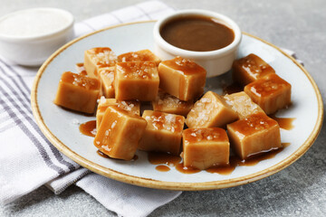 Tasty candies with salt and caramel sauce on grey textured table, closeup