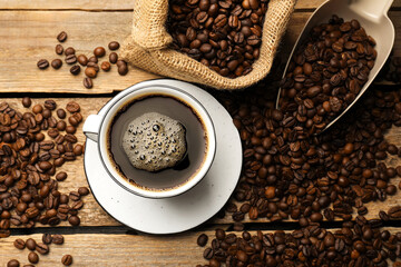 Aromatic coffee in cup and beans on wooden table, flat lay