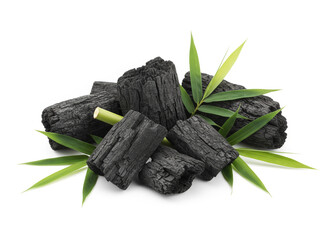 natural composition features several pieces of black charcoal chunks and a wooden bowl filled with fine black charcoal powder. A small wooden scoop holds more powder, and fresh green bamboo leaves add