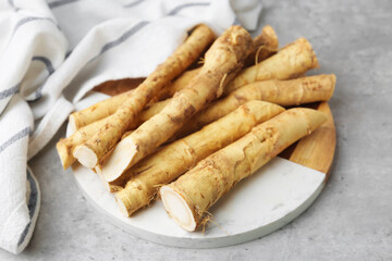 Fresh raw horseradish roots on light grey table, closeup