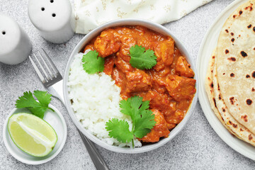 Delicious chicken tikka masala served on grey textured table, flat lay