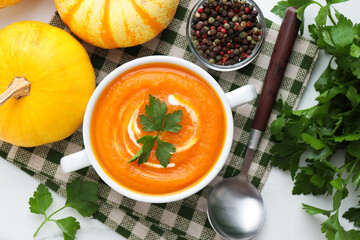 Tasty pumpkin cream soup served on white marble table, flat lay